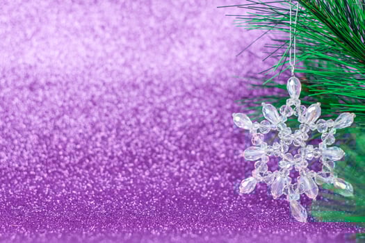 Crystal snowflake on the Christmas tree. Snowflake on a purple background. photo
