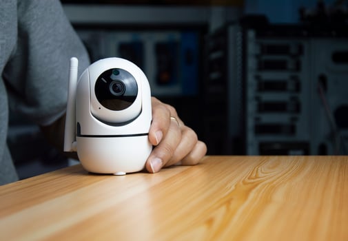 White ip camera lies on wooden floor, man using ip camera photo