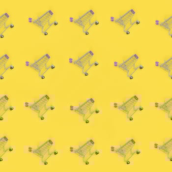 Shopping addiction, shopping lover or shopaholic concept. Many small empty shopping carts perform a pattern on a pastel colored paper background. Flat lay composition, top view photo