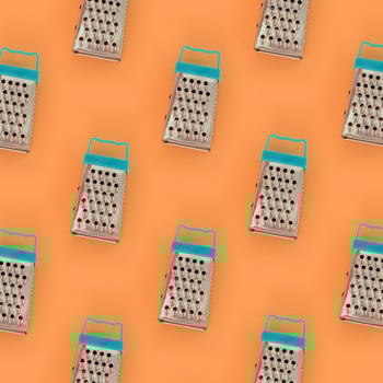 Small stainless steel graters lies on a pastel colored paper. Kitchen accessories. Tools for cooking. Flat lay top view photo
