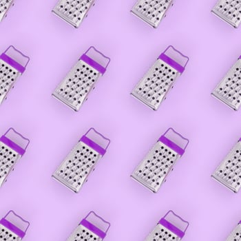 Small stainless steel graters lies on a pastel colored paper. Kitchen accessories. Tools for cooking. Flat lay top view photo