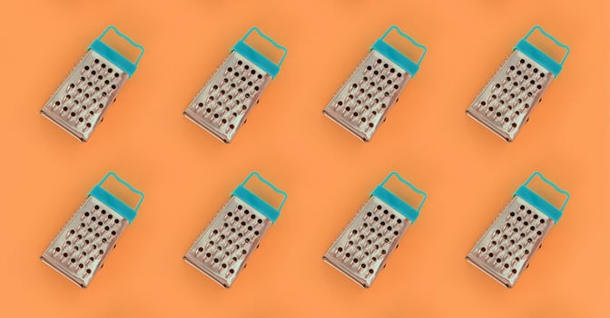 Small stainless steel graters lies on a pastel colored paper. Kitchen accessories. Tools for cooking. Flat lay top view photo