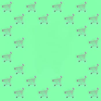 Shopping addiction, shopping lover or shopaholic concept. Many small empty shopping carts perform a pattern on a pastel colored paper background. Flat lay composition, top view photo