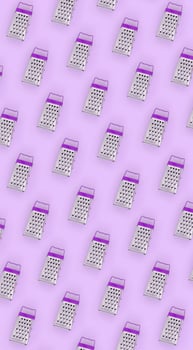 Small stainless steel graters lies on a pastel colored paper. Kitchen accessories. Tools for cooking. Flat lay top view photo