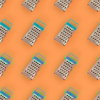 Small stainless steel graters lies on a pastel colored paper. Kitchen accessories. Tools for cooking. Flat lay top view photo