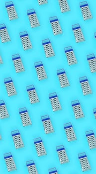 Small stainless steel graters lies on a pastel colored paper. Kitchen accessories. Tools for cooking. Flat lay top view photo