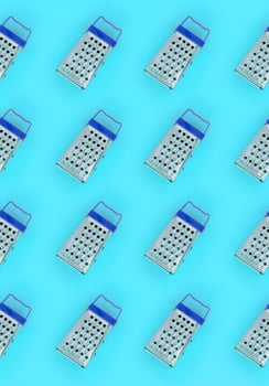 Small stainless steel graters lies on a pastel colored paper. Kitchen accessories. Tools for cooking. Flat lay top view photo