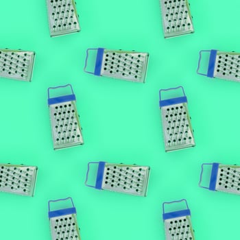 Small stainless steel graters lies on a pastel colored paper. Kitchen accessories. Tools for cooking. Flat lay top view photo