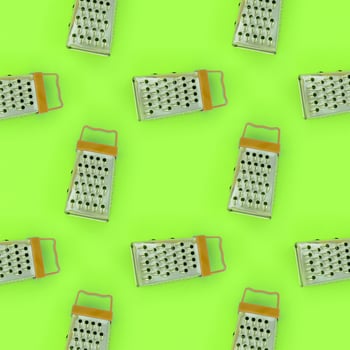 Small stainless steel graters lies on a pastel colored paper. Kitchen accessories. Tools for cooking. Flat lay top view photo