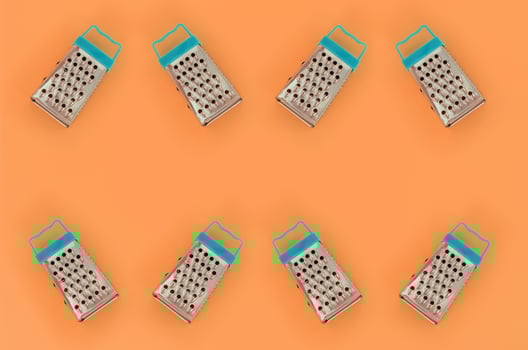 Small stainless steel graters lies on a pastel colored paper. Kitchen accessories. Tools for cooking. Flat lay top view photo