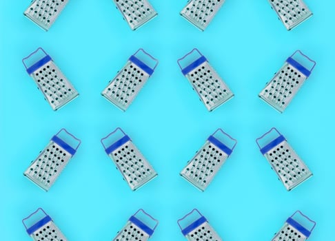 Small stainless steel graters lies on a pastel colored paper. Kitchen accessories. Tools for cooking. Flat lay top view photo