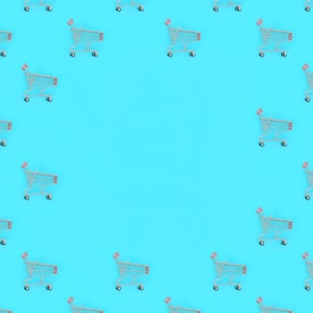 Shopping addiction, shopping lover or shopaholic concept. Many small empty shopping carts perform a pattern on a pastel colored paper background. Flat lay composition, top view photo
