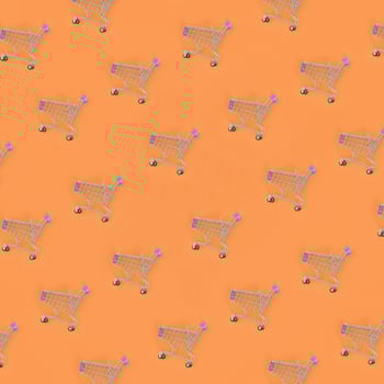 Shopping addiction, shopping lover or shopaholic concept. Many small empty shopping carts perform a pattern on a pastel colored paper background. Flat lay composition, top view photo
