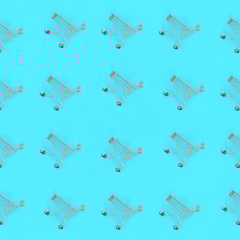 Shopping addiction, shopping lover or shopaholic concept. Many small empty shopping carts perform a pattern on a pastel colored paper background. Flat lay composition, top view photo
