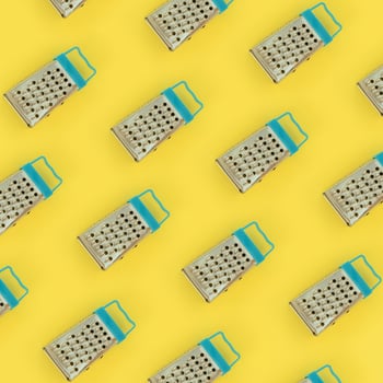 Small stainless steel graters lies on a pastel colored paper. Kitchen accessories. Tools for cooking. Flat lay top view photo