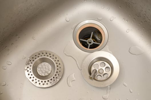 Silvery kitchen sink with a disassembled protective filter during the repair process photo