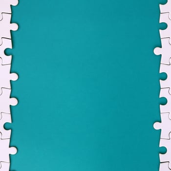 Fragment of a folded white jigsaw puzzle on the background of a blue plastic surface. Texture photo with copy space for text
