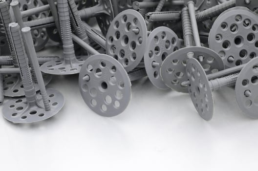 Background of many gray plastic dowels fastening for thermal insulation. A huge pile of plastic bolts with round holey hats lies on a gray foam polystyrene plate photo