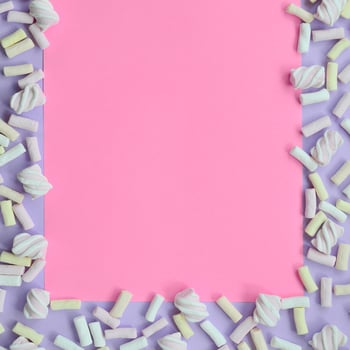 Colorful marshmallow laid out on violet and pink paper background. pastel creative textured framework. minimal photo