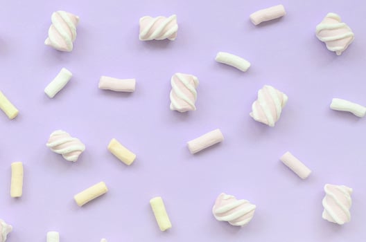 Colorful marshmallow laid out on violet paper background. pastel creative texture. minimal photo