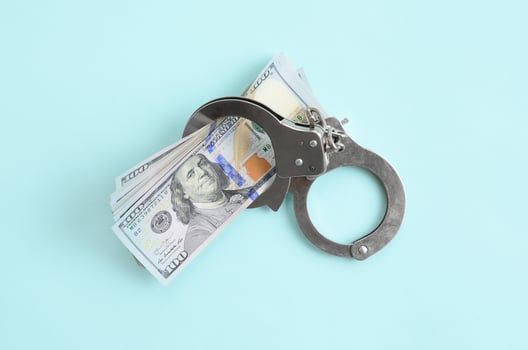 Silver police handcuffs and hundred dollar bills lies on light blue background photo