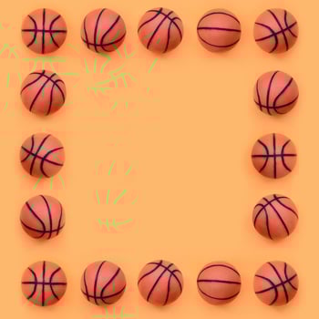 Frame of a many small orange balls for basketball sport game lies on texture background of fashion pastel orange color paper in minimal concept photo