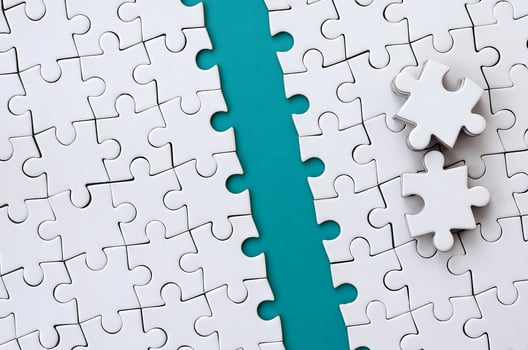 The blue path is laid on the platform of a white folded jigsaw puzzle. The missing elements of the puzzle are stacked nearby. Texture image with space for text photo