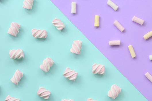 Colorful marshmallow laid out on violet and blue paper background. pastel creative textured pattern. minimal photo