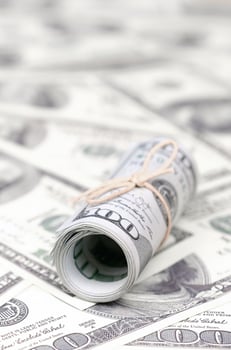 US dollars rolled up and tightened with band lies on a lot of american banknotes with blurred background photo