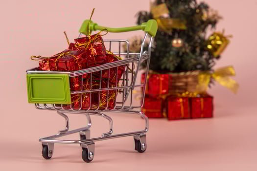 Christmas shopping cart with gifts and Christmas tree in background photo