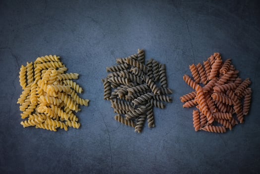 Pasta raw macaroni on black background, close up raw macaroni spiral pasta uncooked delicious whole grain fusilli pasta for cooking food - top view photo