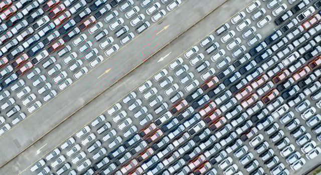 Aerial view of new cars stock at factory parking lot. Above view many cars parked in a row. Automotive industry. Logistics and supply chain business. Import or export new cars at warehouse near port. photo