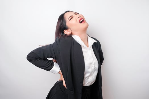 Tired upset young businesswoman suffering from back pain, muscle spasm at workplace. Fatigue, deadline, pain and incorrect posture photo