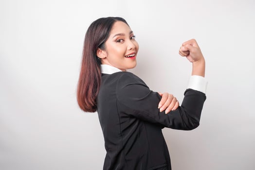 Excited Asian business woman wearing a black suit showing strong gesture by lifting her arms and muscles smiling proudly photo