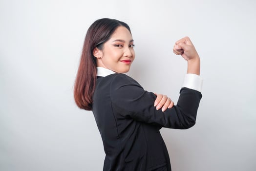 Excited Asian business woman wearing a black suit showing strong gesture by lifting her arms and muscles smiling proudly photo