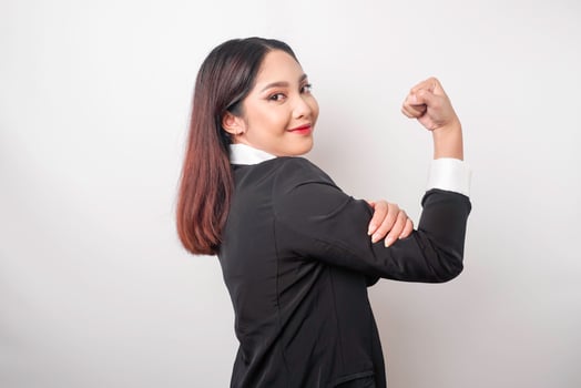Excited Asian business woman wearing a black suit showing strong gesture by lifting her arms and muscles smiling proudly photo