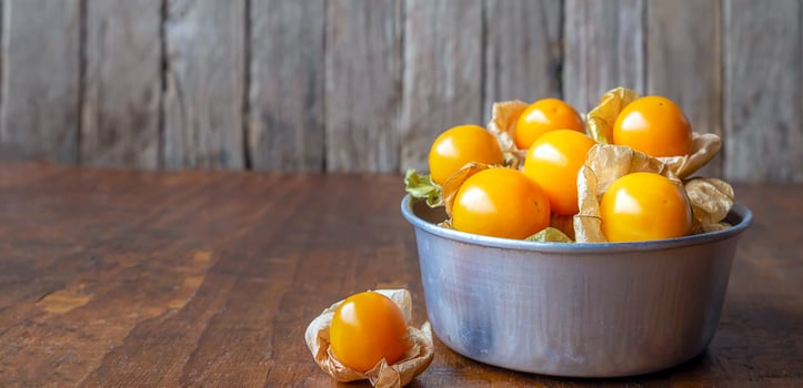 Close-up ripe yellow Cape Gooseberry fruit In a bowl stainless steel on a wooden background photo