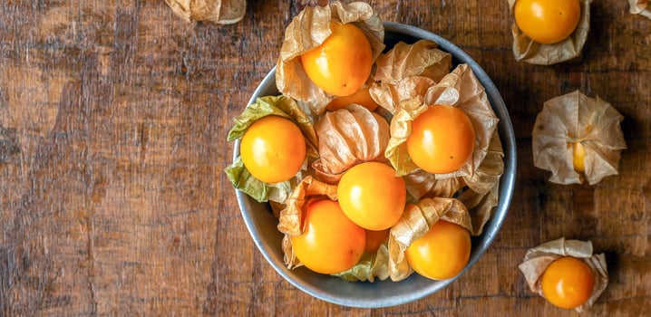 Top view of ripe yellow Cape Gooseberry fruit In a bowl of stainless steel on a wooden background photo