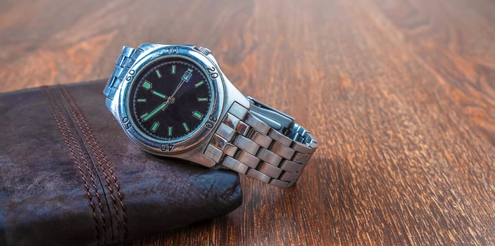 Men's stainless steel watch and brown leather wallet on wooden floor. photo