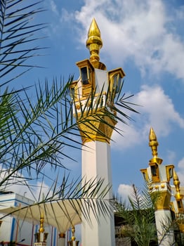 brown gold white color mosque minaret with arabic architecture in madiun indonesia park, sunny weather. photo