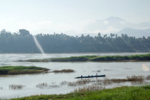Tropical landscape on Mekong River with boat, palm trees and mountains on the bank in sunlight. Luang Prabang, Laos. photo