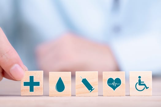 Businessman chooses a emoticon icons healthcare medical symbol on wooden block , Healthcare and medical Insurance concept photo