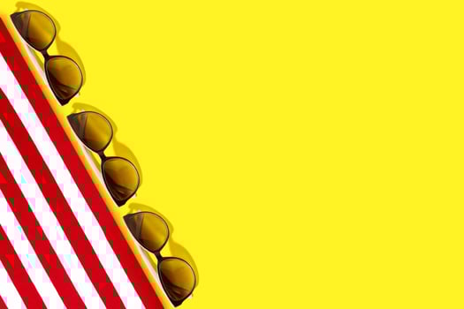 Red-white sunbed or towel, sunglasses, straw hat, seashells on a yellow background. Travel and tourism. Copy space photo
