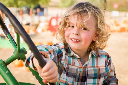 Adorable Young Boy Playing on an Old Tractor Outside photo