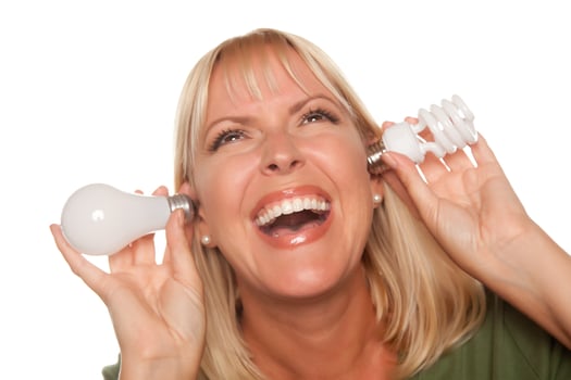Funny Woman Holding Energy Saving and Regular Light Bulbs to Her Ears photo