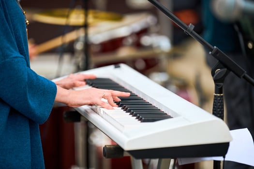 Musician woman playing on synthesizer keyboard piano, hands press synthesizer keys on concert stage photo