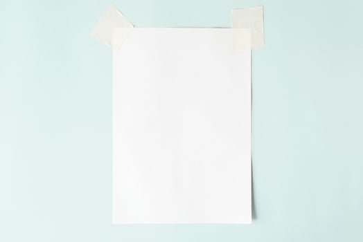 White sheet on scotch tape, layout. Blank sheet of paper on a pastel blue background, copy space photo