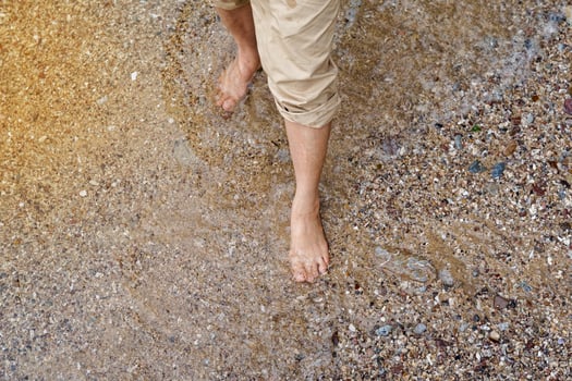 An Asian woman folds up her pant legs to prevent them from getting wet while wading on the beach. Soft and selective focus. photo