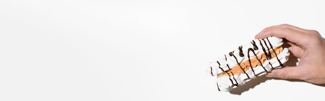 Hand holding meringue cake on a white background, copy space. Sweet banner, top view photo