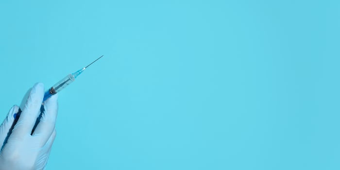 Vaccination concept. Doctor's hand in medical gloves holding a syringe injection. Banner, copy space, top view photo